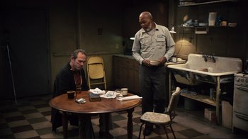 Movie still from “The Sunset Limited” (2011), directed by Tommy Lee Jones – Two men are sitting at a table in a kitchen; Wide shot, High angle