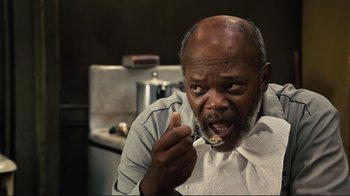 Movie still from “The Sunset Limited” (2011), directed by Tommy Lee Jones – An older man is eating food from a spoon; Close Up shot, Over the shoulder angle