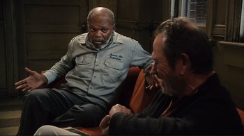 Movie still from “The Sunset Limited” (2011), directed by Tommy Lee Jones – Two men are sitting on a couch and talking to each other; Medium shot, Over the shoulder angle