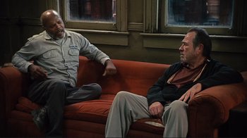 Movie still from “The Sunset Limited” (2011), directed by Tommy Lee Jones – Two men are sitting on a red couch talking; Medium shot, High angle