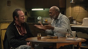 Movie still from “The Sunset Limited” (2011), directed by Tommy Lee Jones – Two men sitting at a table talking to each other; Medium shot, Over the shoulder angle