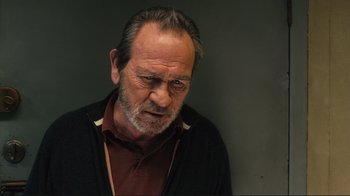 Movie still from “The Sunset Limited” (2011), directed by Tommy Lee Jones – An older man with a beard and mustache wearing a black sweater; Close Up shot, Low angle