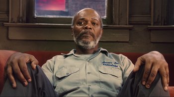 Movie still from “The Sunset Limited” (2011), directed by Tommy Lee Jones – An older man sitting on a red couch in front of a window; Close Up shot, Low angle