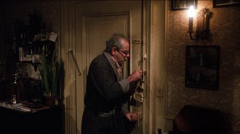 Movie still from “The Sunshine Boys” (1975), directed by Herbert Ross – An older man in a suit and tie fixing a wall; Medium shot, High angle