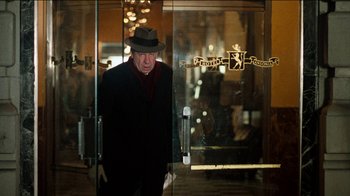 Movie still from “The Sunshine Boys” (1975), directed by Herbert Ross – An older man wearing a hat walking through a door way; Medium shot, Over the shoulder angle