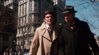 Movie still from “The Sunshine Boys” (1975), directed by Herbert Ross – A man in a trench coat standing next to another man in a hat; Medium shot, Low angle