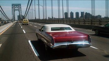 Movie still from “The Sunshine Boys” (1975), directed by Herbert Ross – A red and white car driving down a road; Wide shot, Low angle