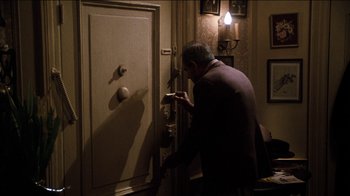 Movie still from “The Sunshine Boys” (1975), directed by Herbert Ross – A man is opening a door in a room; Medium shot, High angle