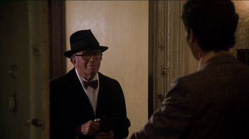 Movie still from “The Sunshine Boys” (1975), directed by Herbert Ross – An older man wearing a hat and a bow tie; Medium shot, Over the shoulder angle