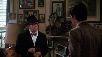 Movie still from “The Sunshine Boys” (1975), directed by Herbert Ross – An older man wearing a hat and a bow tie talking to a young man; Medium shot, Over the shoulder angle
