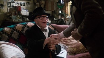 Movie still from “The Sunshine Boys” (1975), directed by Herbert Ross – An older man wearing a suit and hat shaking hands with a younger man; Medium shot, Over the shoulder angle