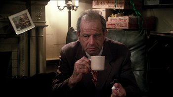 Movie still from “The Sunshine Boys” (1975), directed by Herbert Ross – An older man sitting in a chair holding a coffee cup; Medium shot, Low angle