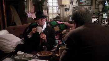 Movie still from “The Sunshine Boys” (1975), directed by Herbert Ross – An older man sitting on a couch drinking a cup of coffee; Medium shot, Over the shoulder angle