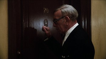 Movie still from “The Sunshine Boys” (1975), directed by Herbert Ross – An older man wearing a suit and tie looking at a door knob; Medium shot, Low angle