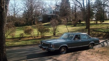 Movie still from “The Sunshine Boys” (1975), directed by Herbert Ross – An older car parked on the side of the road near a house; Extreme Wide shot, High angle