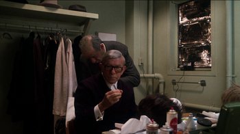 Movie still from “The Sunshine Boys” (1975), directed by Herbert Ross – A man sitting at a table with another man standing next to him; Medium shot, Over the shoulder angle