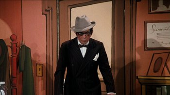 Movie still from “The Sunshine Boys” (1975), directed by Herbert Ross – A man in a suit and a hat is standing in front of a door; Medium shot, High angle
