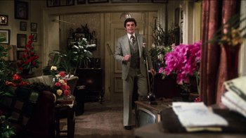 Movie still from “The Sunshine Boys” (1975), directed by Herbert Ross – A man in a suit and tie standing in a living room; Wide shot, Over the shoulder angle