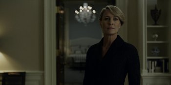 Movie still from “House of Cards” (2013), created by Beau Willimon – A woman standing in a room in front of a chandelier; Medium shot, Low angle