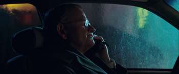 Movie still from “The Sweet Hereafter” (1997), directed by Atom Egoyan – An older man sitting in the back of a car talking on a cell phone; Close Up shot, Over the shoulder angle