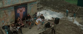 Movie still from “The Sweet Hereafter” (1997), directed by Atom Egoyan – A group of people playing instruments on a stage; Wide shot, High angle