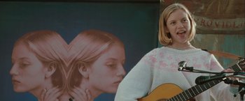 Movie still from “The Sweet Hereafter” (1997), directed by Atom Egoyan – A woman standing next to a painting of a girl with blonde hair; Medium shot, Low angle