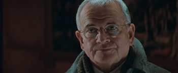 Movie still from “The Sweet Hereafter” (1997), directed by Atom Egoyan – An older man wearing glasses and a sweater; Close Up shot, Over the shoulder angle