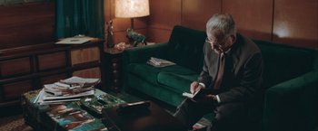 Movie still from “The Sweet Hereafter” (1997), directed by Atom Egoyan – An older man sitting in front of a green couch; Medium shot, High angle