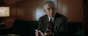 Movie still from “The Sweet Hereafter” (1997), directed by Atom Egoyan – An older man wearing a suit and tie holding a cell phone; Close Up shot, Over the shoulder angle