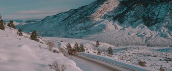 A truck driving down a snow covered mountain road