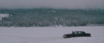 Movie still from “The Sweet Hereafter” (1997), directed by Atom Egoyan – A man driving a car in the snow near a forest; Extreme Wide shot, High angle