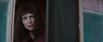 Movie still from “The Sweet Hereafter” (1997), directed by Atom Egoyan – A woman standing next to a door in a dark room; Close Up shot, High angle
