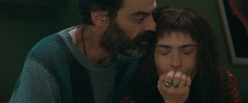 Movie still from “The Sweet Hereafter” (1997), directed by Atom Egoyan – A man and a woman kissing each other in front of a wall; Close Up shot, Overhead angle