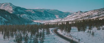 Movie still from “The Sweet Hereafter” (1997), directed by Atom Egoyan – A road going through a snow covered forest; Extreme Wide shot, High angle
