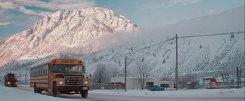 A school bus driving down a street in the snow