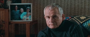 Movie still from “The Sweet Hereafter” (1997), directed by Atom Egoyan – An older man sitting in front of a picture of himself; Close Up shot, Over the shoulder angle