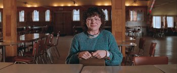 Movie still from “The Sweet Hereafter” (1997), directed by Atom Egoyan – An older woman sitting at a wooden table; Medium shot, Over the shoulder angle