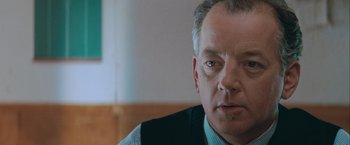 Movie still from “The Sweet Hereafter” (1997), directed by Atom Egoyan – An older man in a vest looking at the camera; Close Up shot, Over the shoulder angle