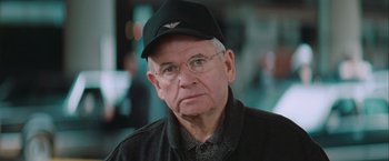Movie still from “The Sweet Hereafter” (1997), directed by Atom Egoyan – An older man wearing glasses and wearing a hat; Close Up shot, High angle