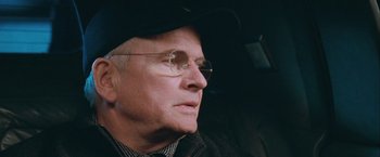 Movie still from “The Sweet Hereafter” (1997), directed by Atom Egoyan – An older man wearing glasses and a black hat; Close Up shot, Over the shoulder angle
