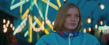 Movie still from “The Sweet Hereafter” (1997), directed by Atom Egoyan – A woman in a blue jacket standing in front of lights; Medium shot, Low angle