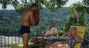 Movie still from “The Swimmer” (1968), directed by Sydney Pollack – A man in black trunks standing next to a man in a striped shirt; Wide shot, Over the shoulder angle