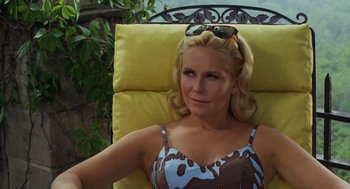 Movie still from “The Swimmer” (1968), directed by Sydney Pollack – A woman sitting in a chair wearing sunglasses; Close Up shot, High angle