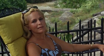 Movie still from “The Swimmer” (1968), directed by Sydney Pollack – A woman sitting in front of a black iron fence; Close Up shot, High angle