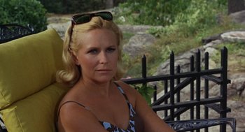 Movie still from “The Swimmer” (1968), directed by Sydney Pollack – A woman sitting in a chair wearing sunglasses; Close Up shot, High angle