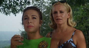 Movie still from “The Swimmer” (1968), directed by Sydney Pollack – Two women standing next to each other in front of trees; Close Up shot, Low angle