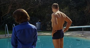 Movie still from “The Swimmer” (1968), directed by Sydney Pollack – A man and a woman standing next to a swimming pool; Medium shot, Over the shoulder angle