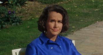 Movie still from “The Swimmer” (1968), directed by Sydney Pollack – An older woman wearing a blue shirt sitting on a bench; Close Up shot, High angle