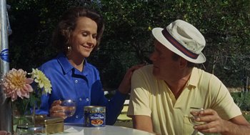 Movie still from “The Swimmer” (1968), directed by Sydney Pollack – A man and a woman sitting at an outdoor table; Medium shot, High angle