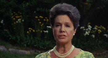 Movie still from “The Swimmer” (1968), directed by Sydney Pollack – An older woman wearing pearls and a green floral dress; Close Up shot, Low angle